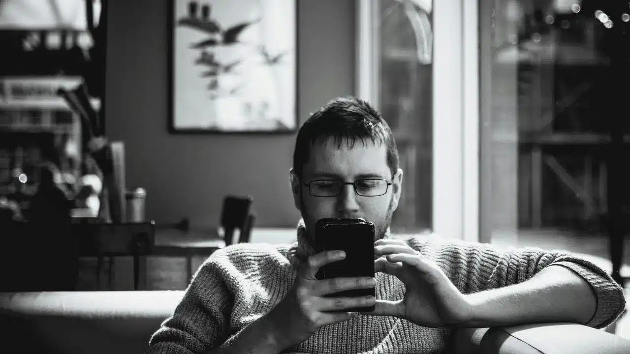 A man sitting on a couch looking at his phone.