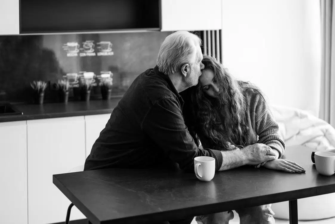 A caring and emotionally safe man hugging his partner.