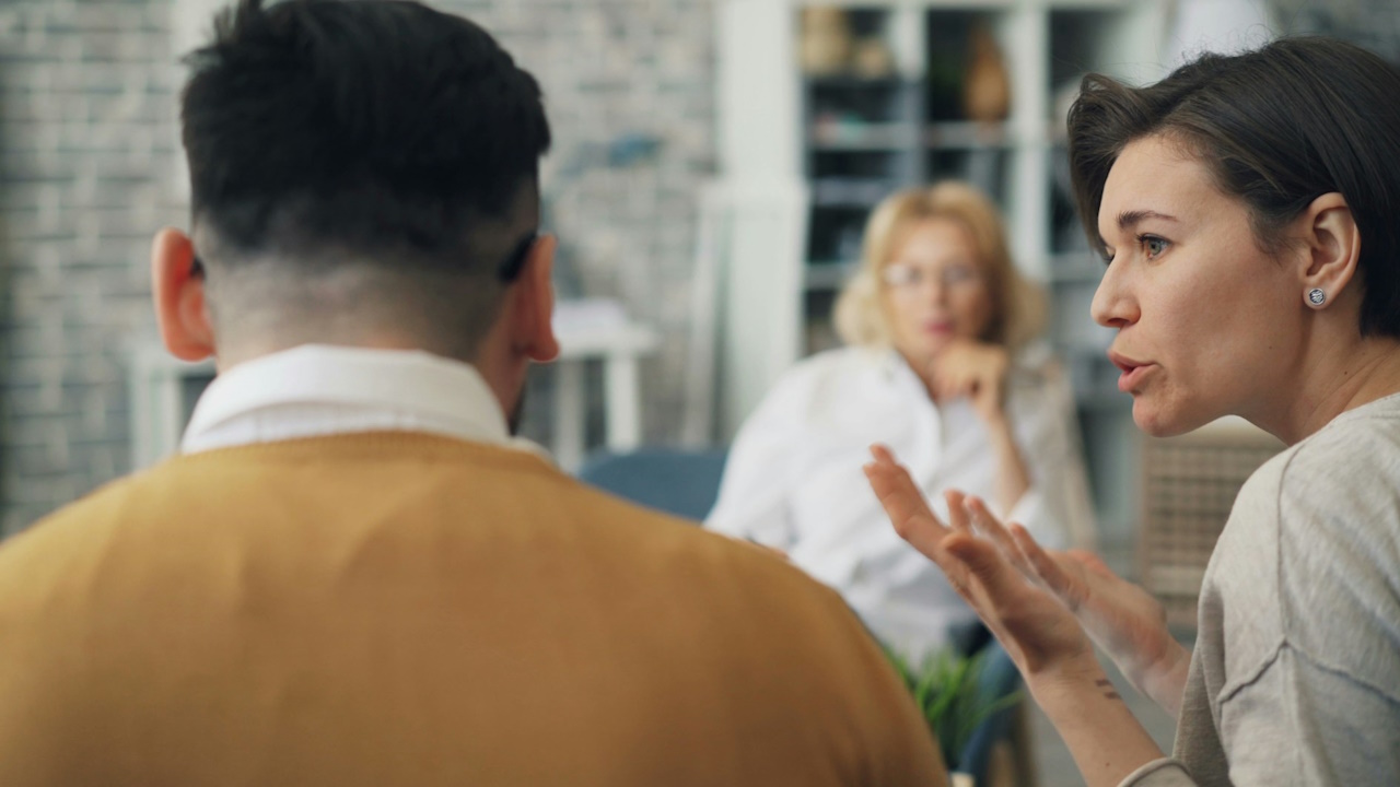 A woman talking to a man at a table.