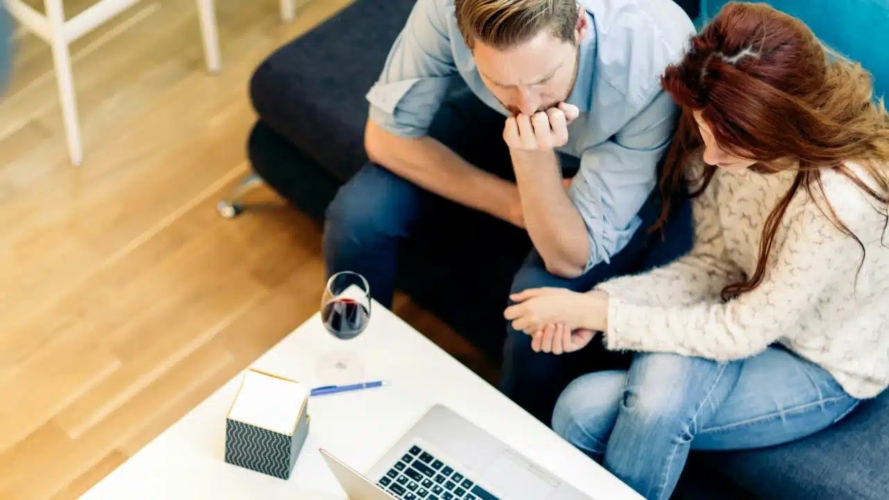 High angle shot of a man and woman sitting on a sofa looking at a laptop.