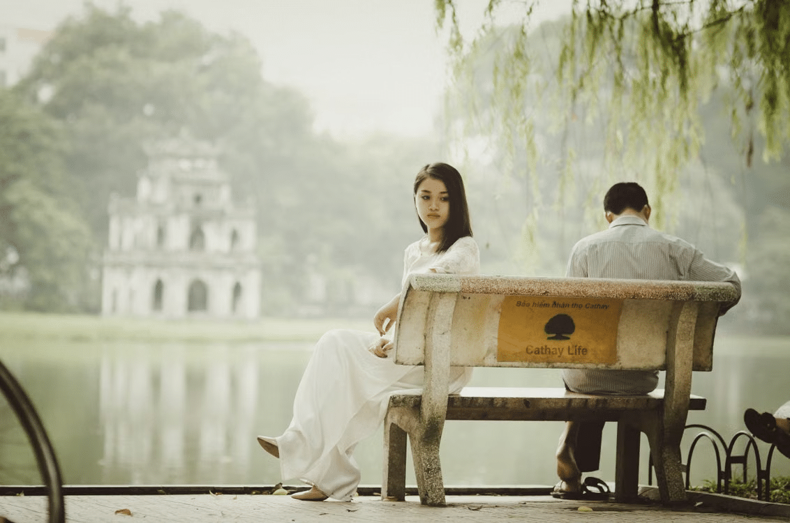 A couple with emotional distance despite sitting on the same bench.