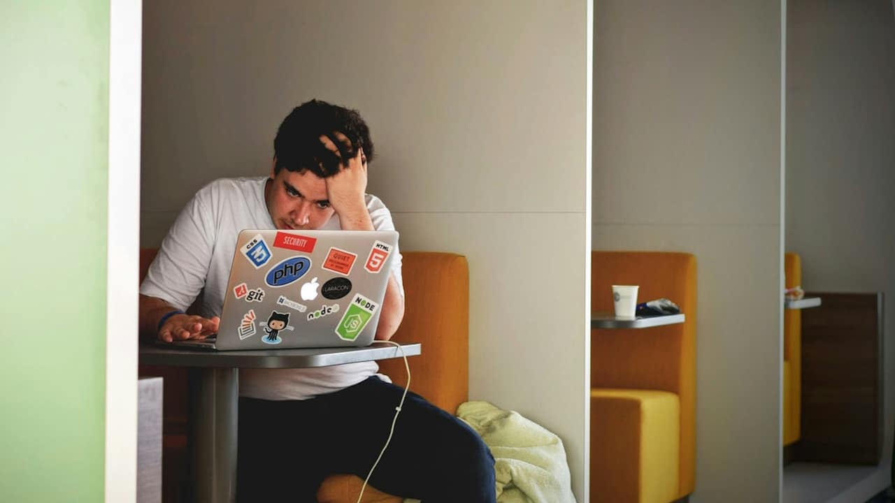 A man working on a laptop and looking flustered.