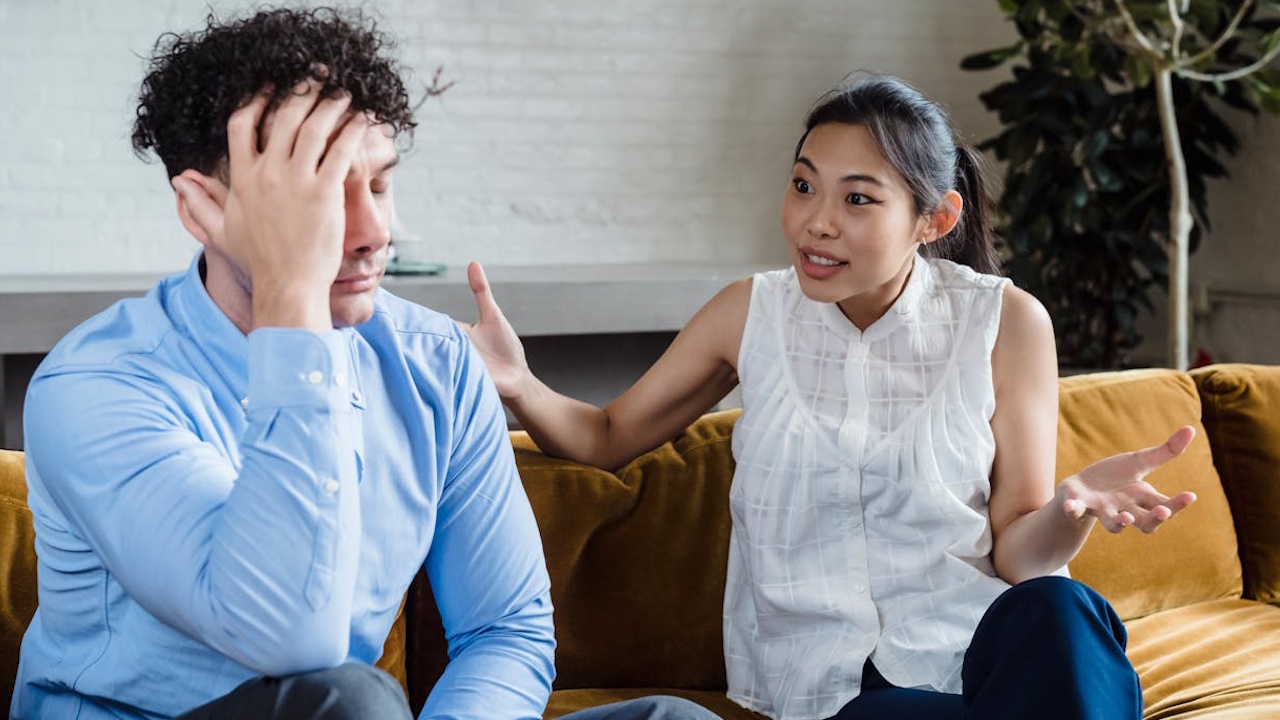 A man and a woman having an argument while sitting on a couch.