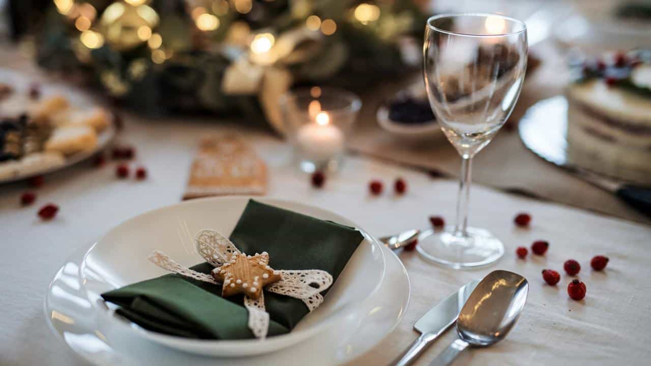 A dinner table set with candles, plates and folded napkins for a special occasion.