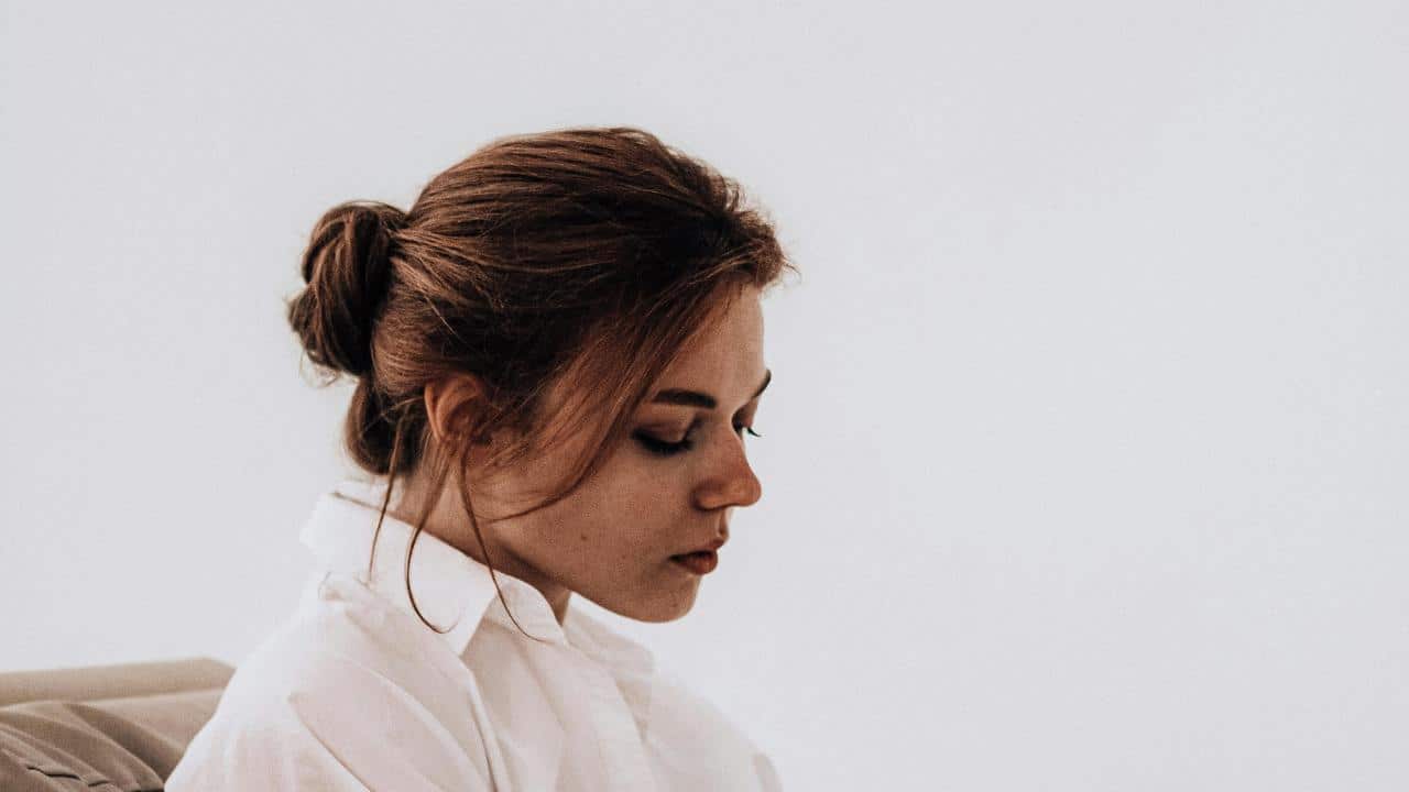A woman sitting quietly with her head lowered.