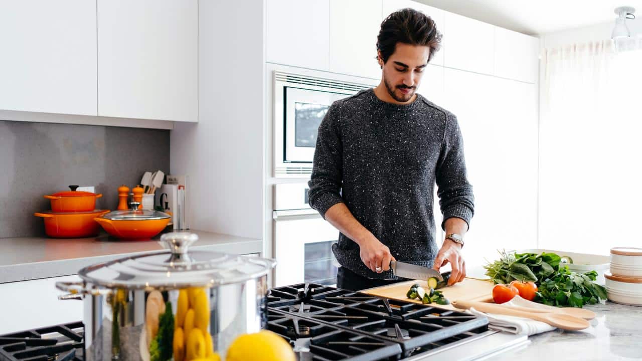 A man chopping vegetables on a cutting board in a modern kitchen.
