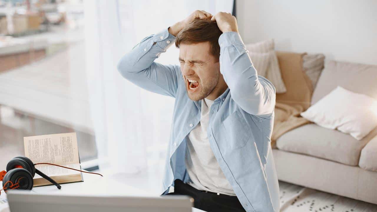 A man yelling and holding his head in frustration.