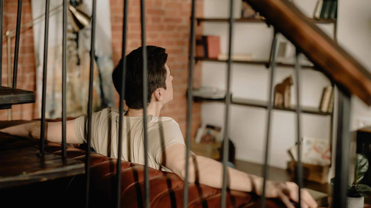 A person sitting on a couch looking toward a bookshelf.
