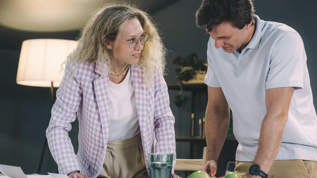 A woman and a man leaning over a table talking.