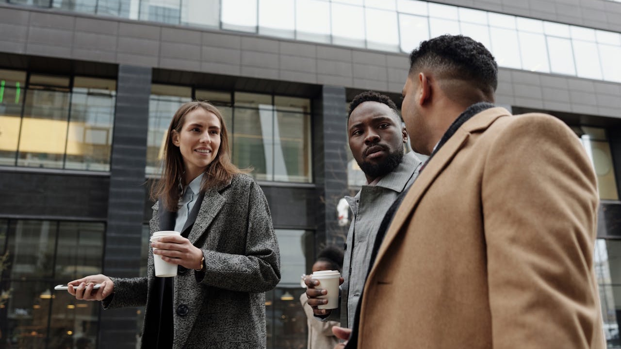 Coworkers walking and talking while having coffee.
