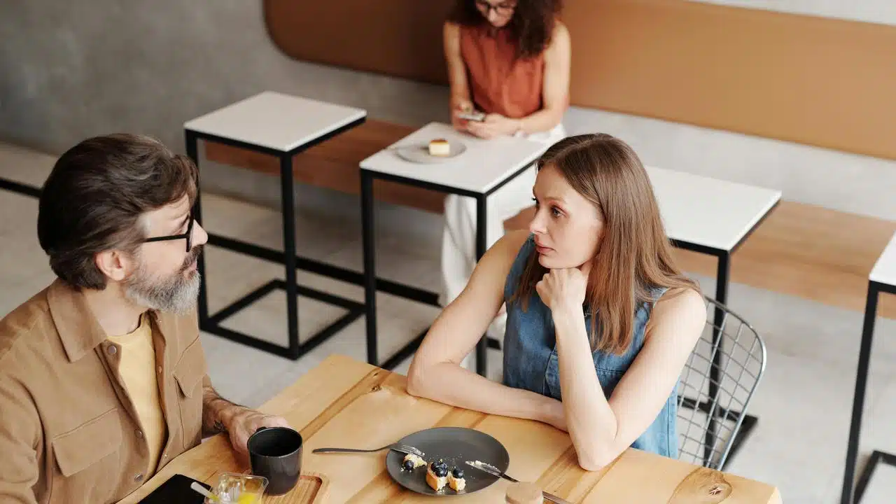 A man and a woman having a conversation at a café table.