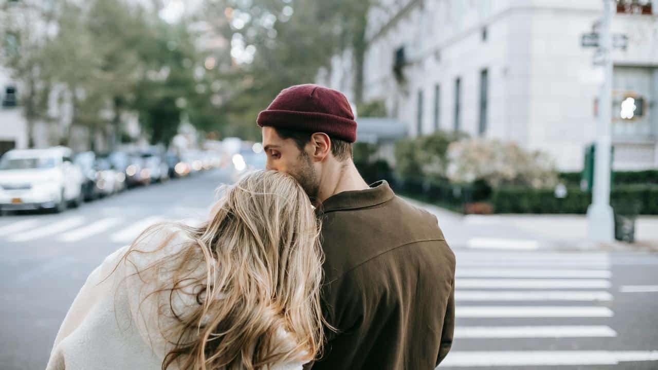 A couple standing close together on a city street.