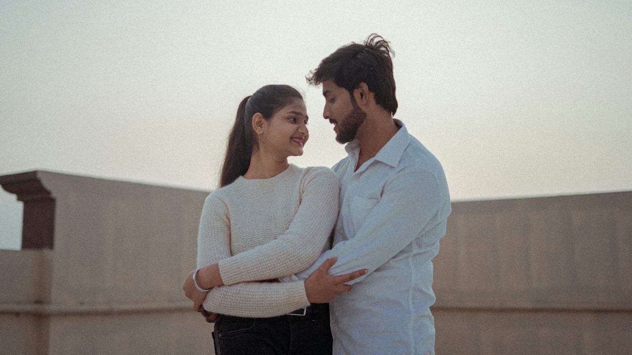 A couple hugging each other while standing on the rooftop of their home.