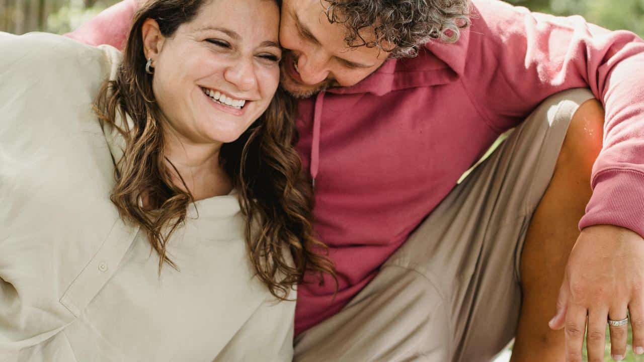 A couple sitting close together smiling and laughing.