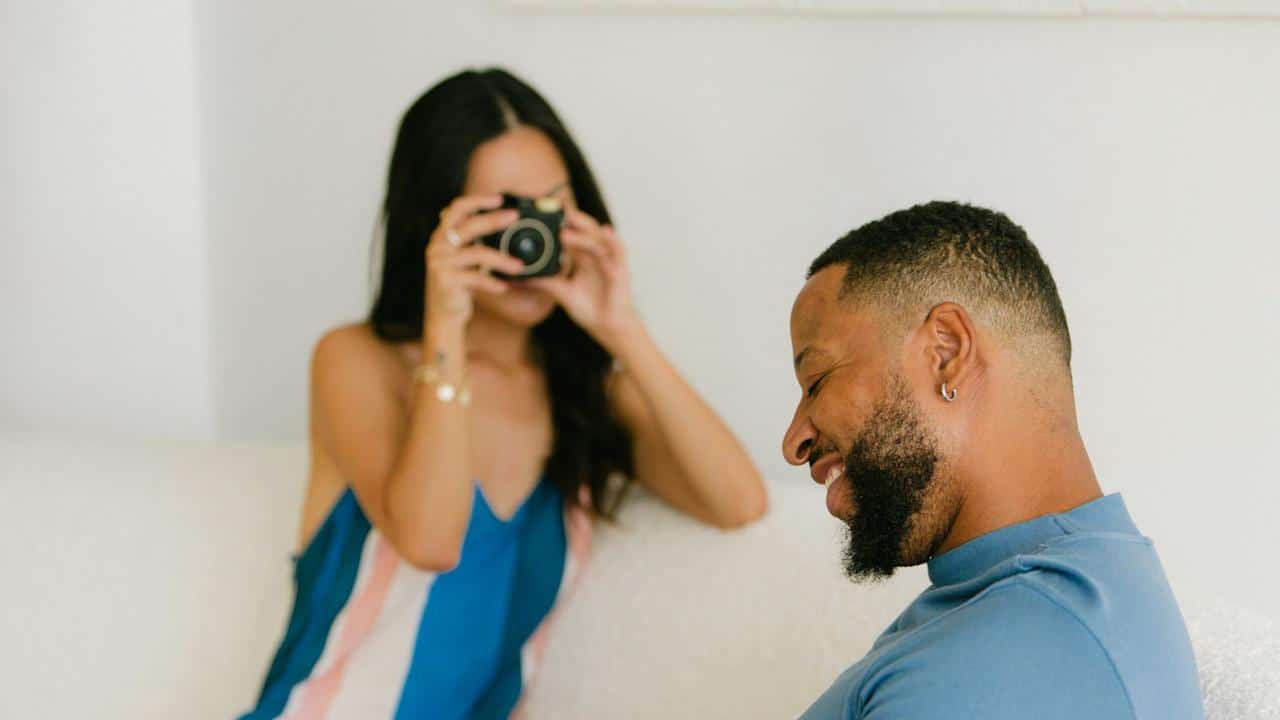 A woman taking a picture of a man with a  camera.