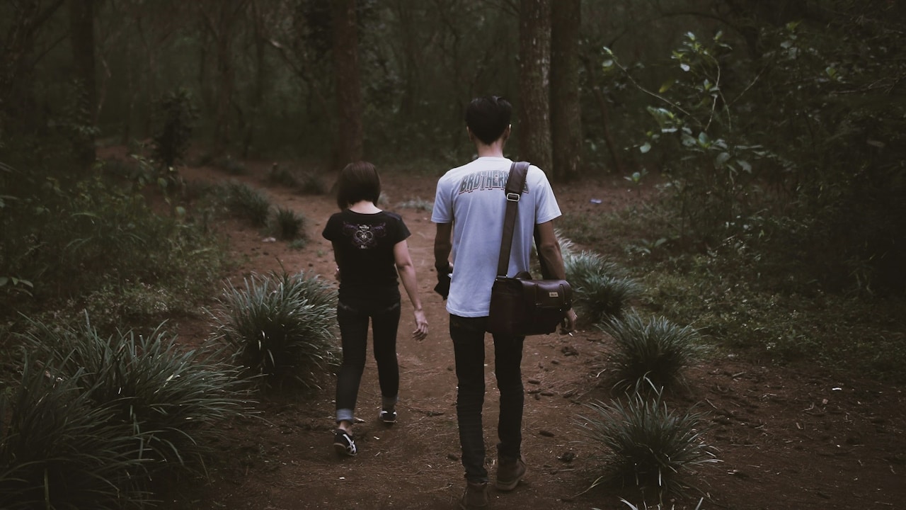 A woman going away from her boyfriend while walking in a forest.