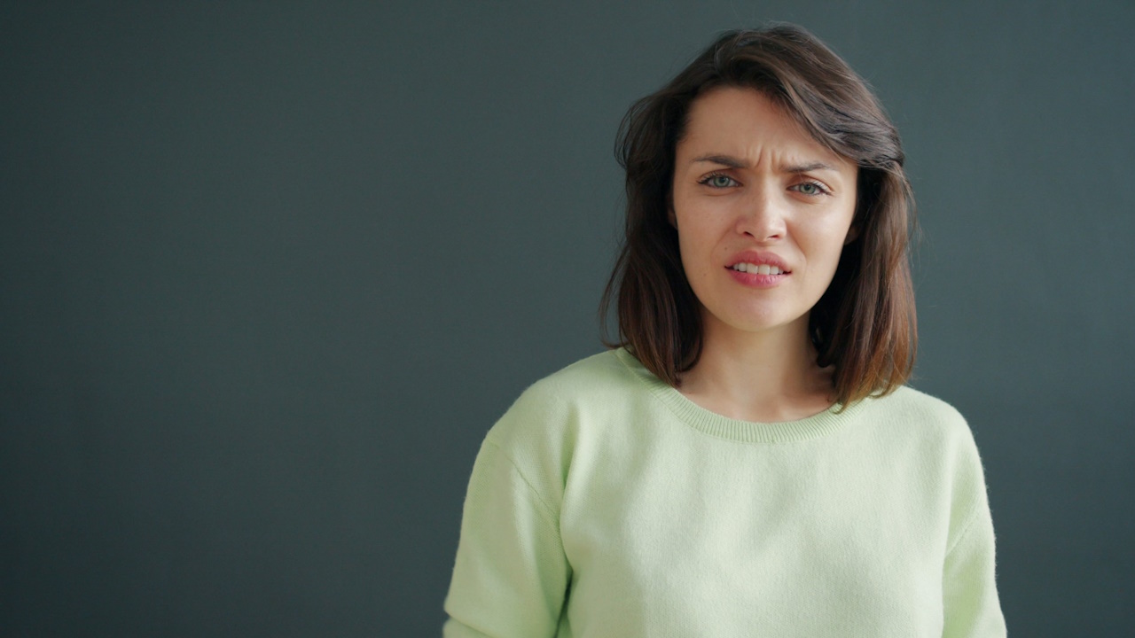 A woman with a disgusted expression against a dark background.