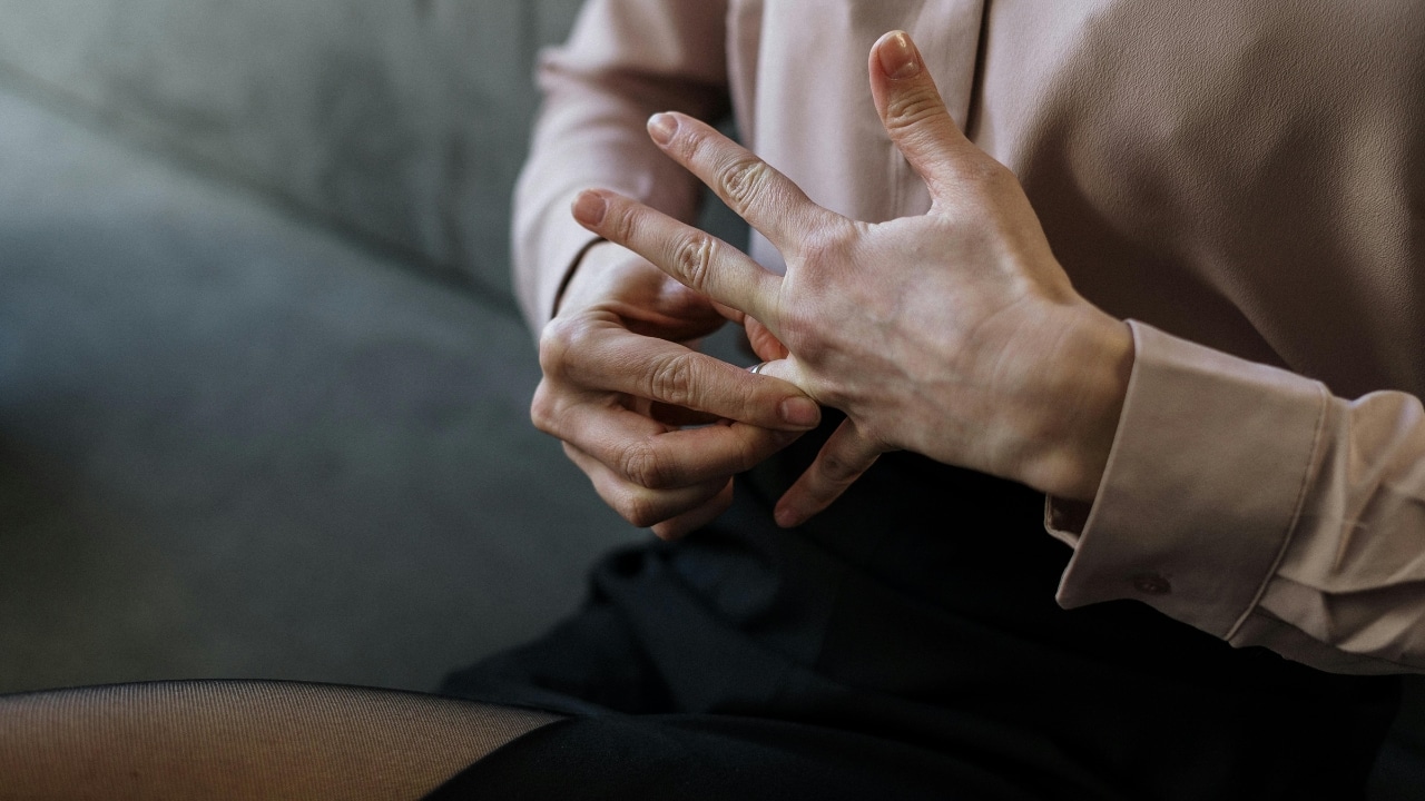 A close-up shot shows a person’s hands slowly removing a thin metal ring from their finger.