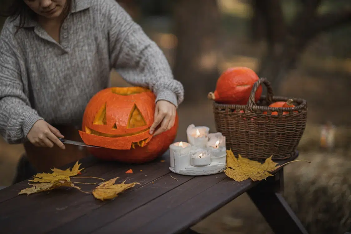 A woman carving a jack-o-lantern.