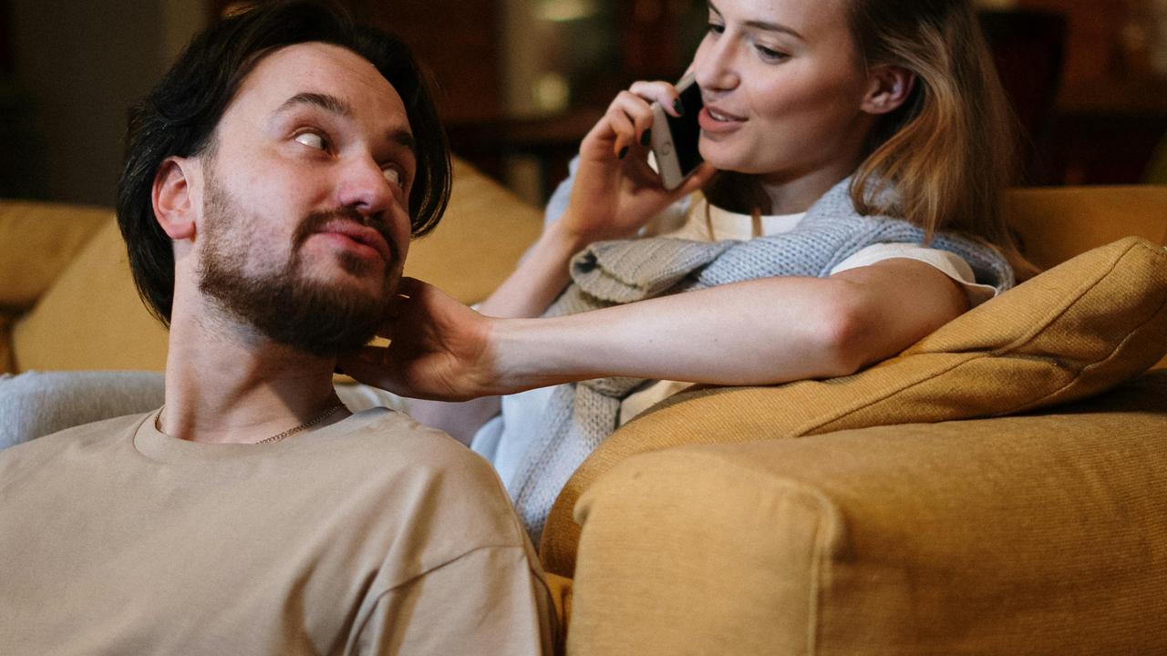 A woman on the phone sitting with a man on a couch.