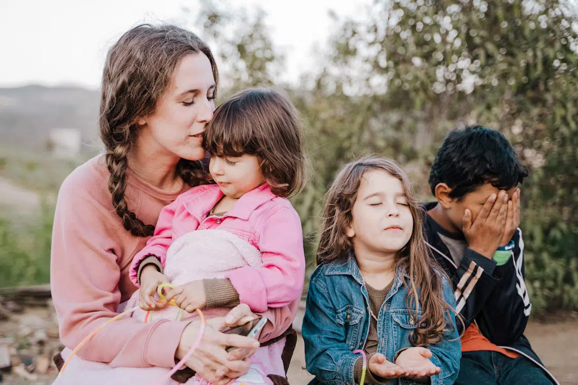 A woman with her three children sitting on a bench outdoors.