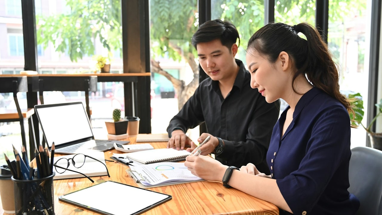 A businesswoman discussing project planning with a colleague at a modern workplace.