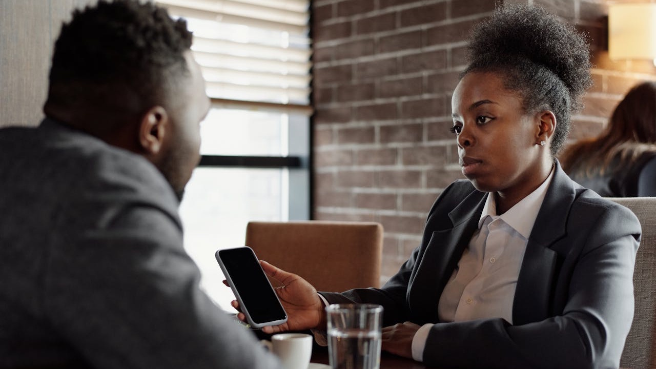 A rude girl showing something on her phone to her boyfriend.