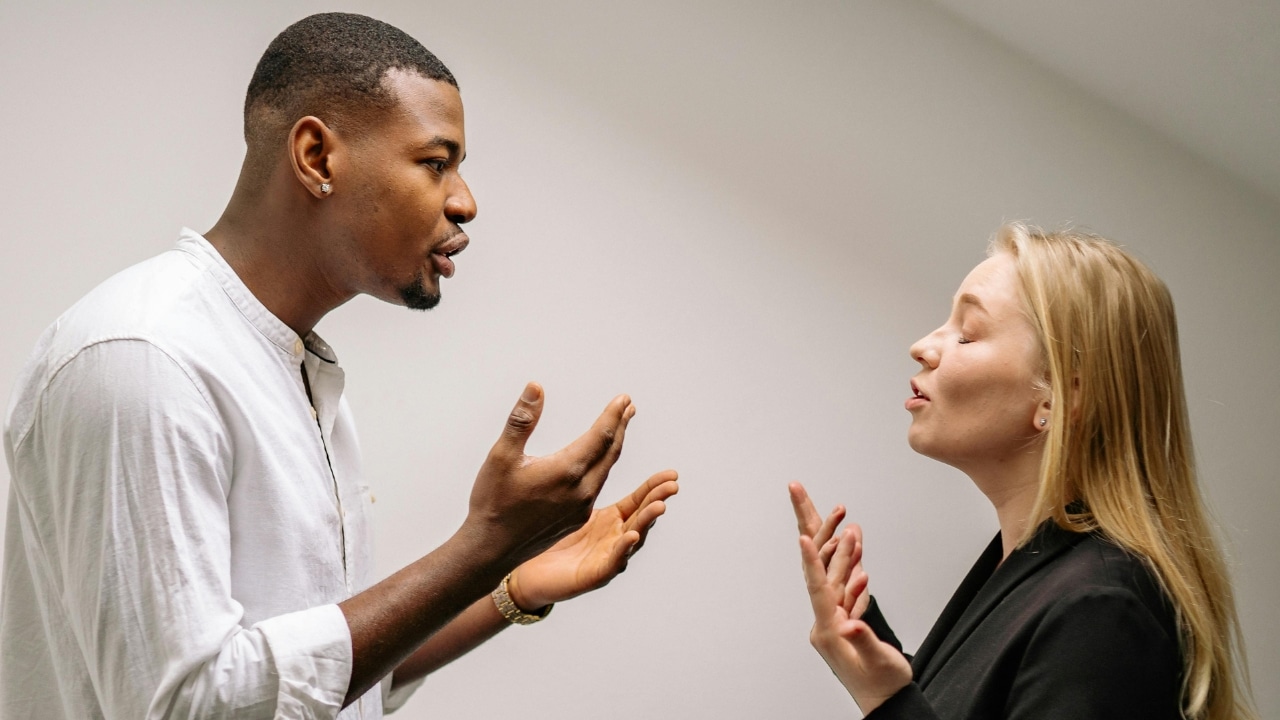 A man and woman face each other with open hands and active expressions during conversation.
