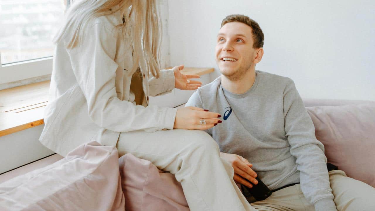 A man smiling up at someone while sitting on a couch.