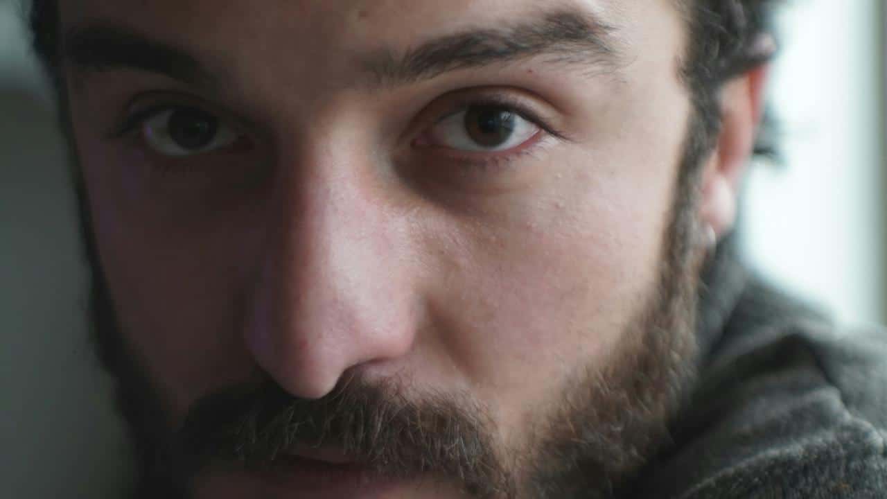 Close-up of a man's face with a beard and intense eyes.