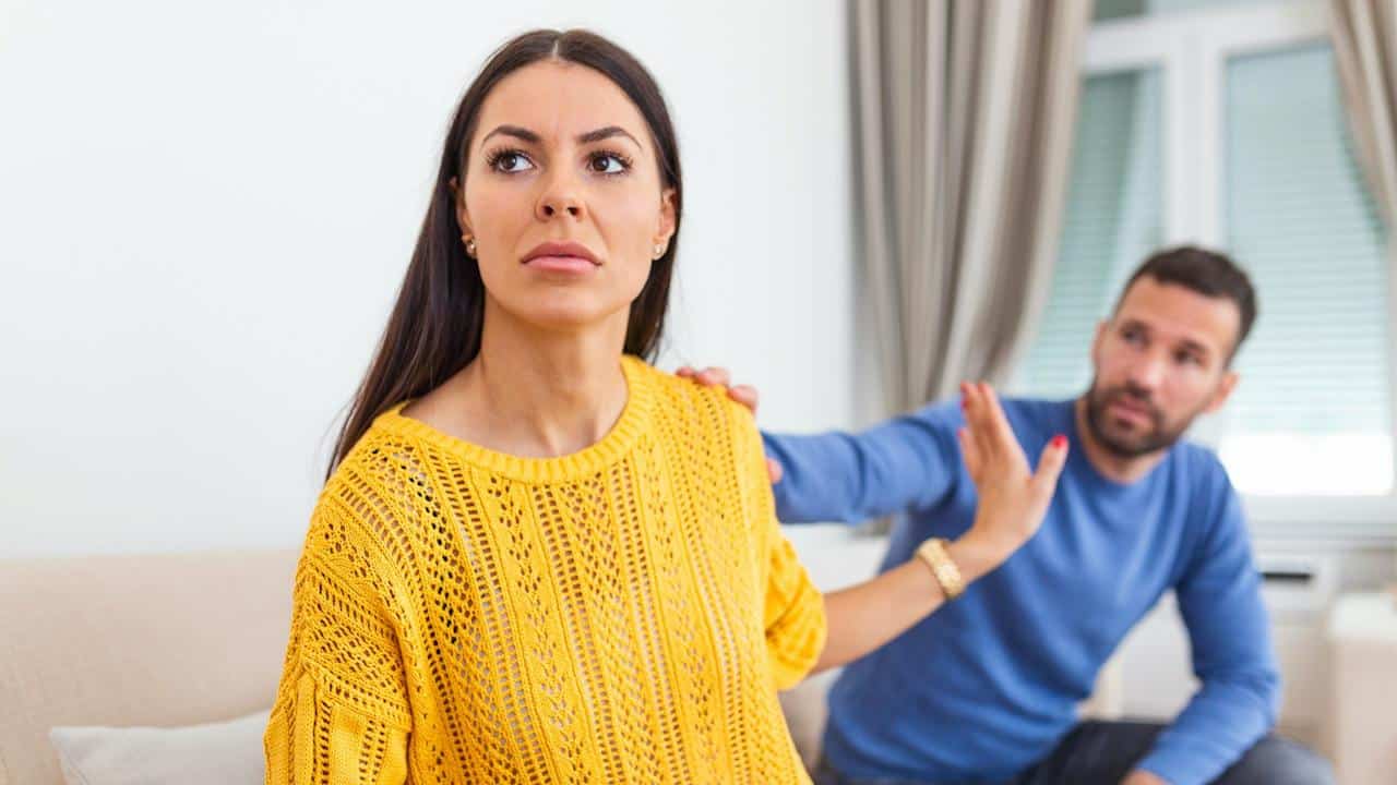 A man is touching the shoulder of a woman; the woman is gesturing to refuse to talk to him.