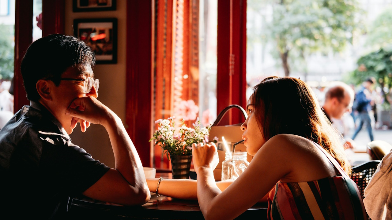 A man staring at a woman sipping on a straw on a date.