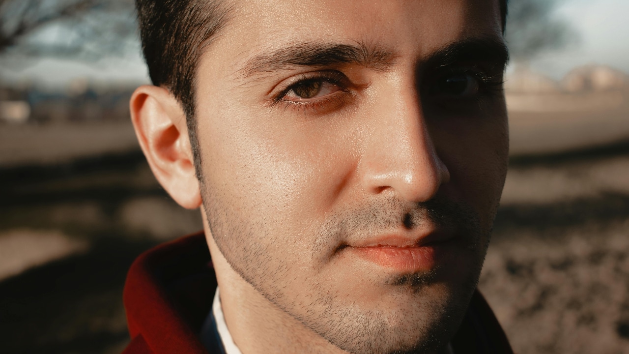 A close-up portrait of a man looking directly forward with soft sunlight on his face.