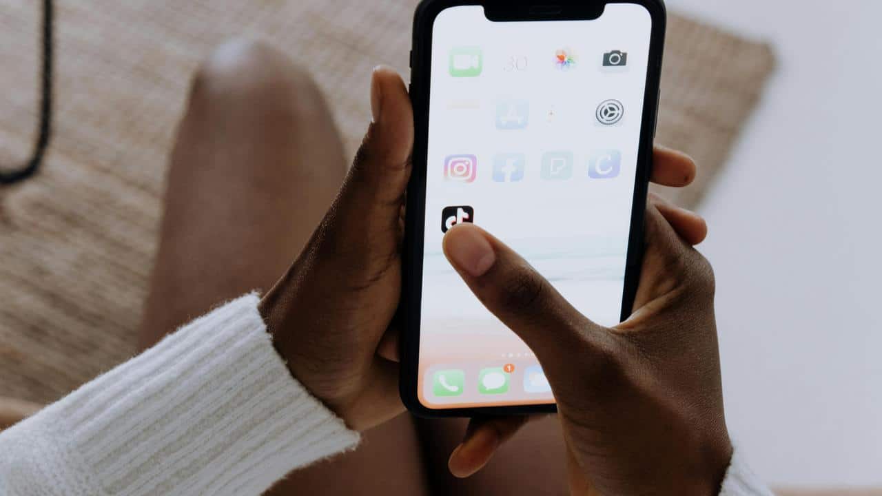 A person tapping an app on a smartphone screen.