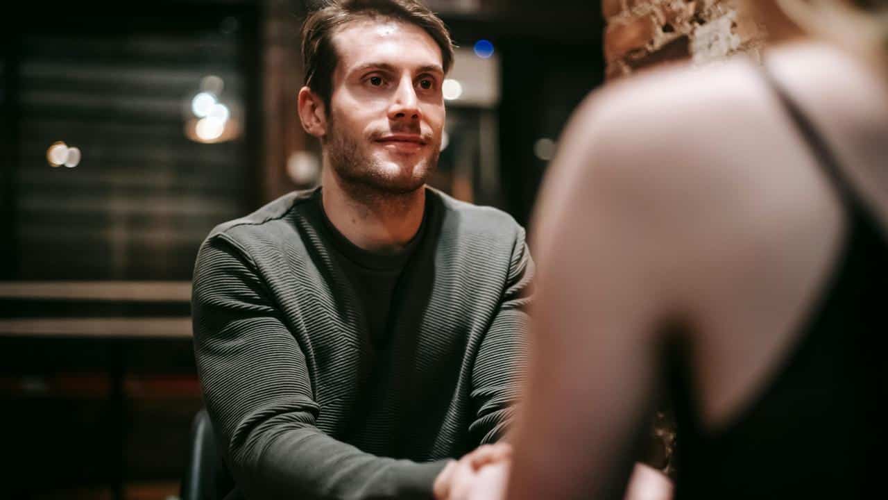 A man holding hands with someone across a table.