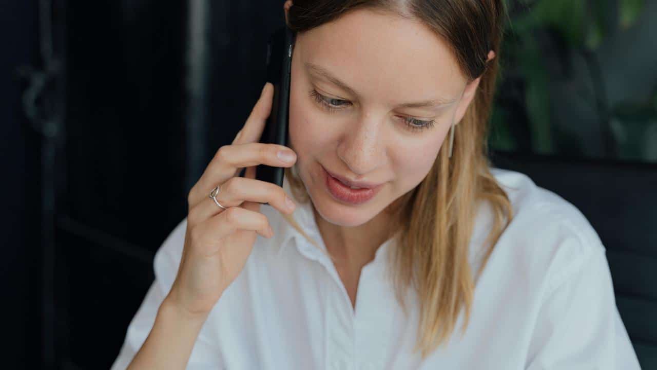 A woman in a white shirt talking on a phone.