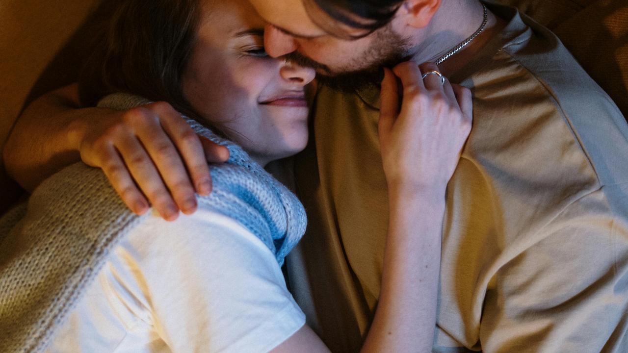 A couple cuddling closely with affectionate smiles.