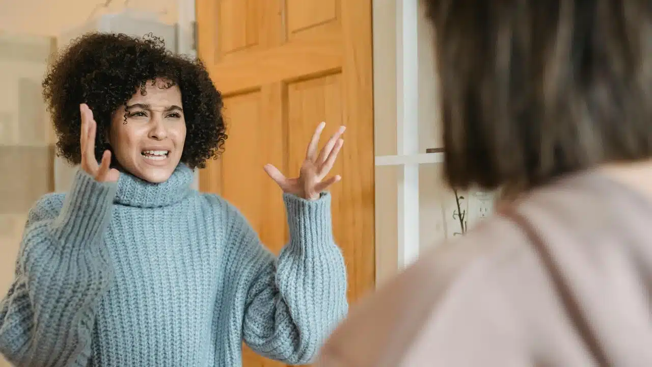 A woman gesturing angrily while arguing with another person.