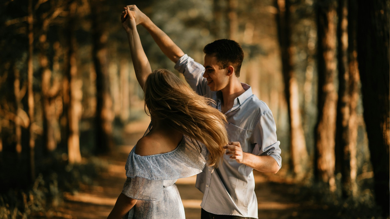 A man and a woman dancing in the middle of a forest.