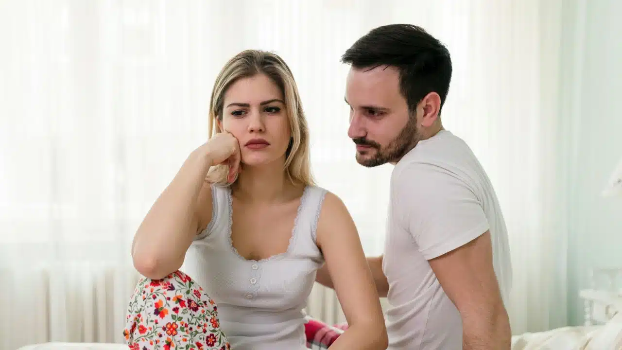 A man in a white shirt looks intently at a woman who is resting her chin.