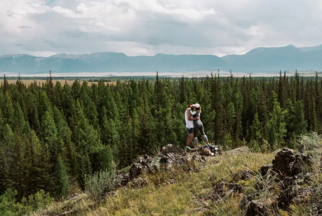 A couple kissing on top of a mountain.