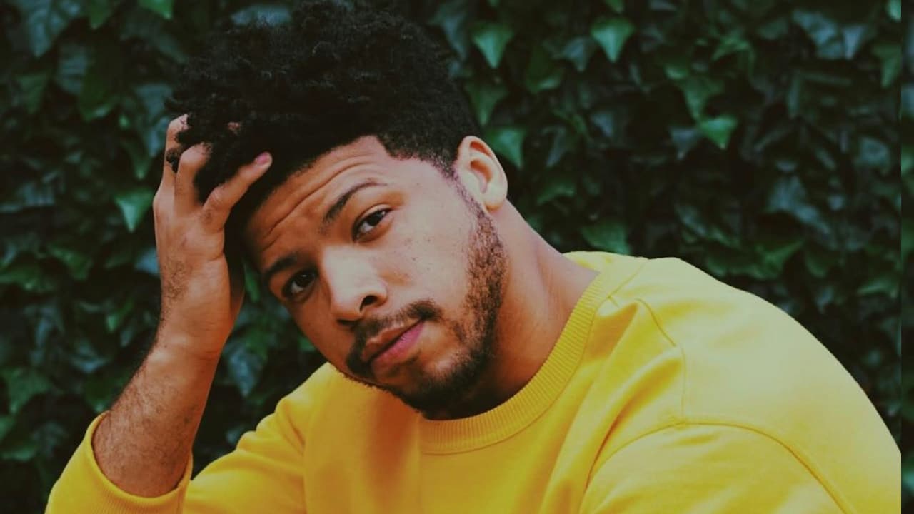 A man in a yellow crew-neck t-shirt sitting on green grass during daytime.