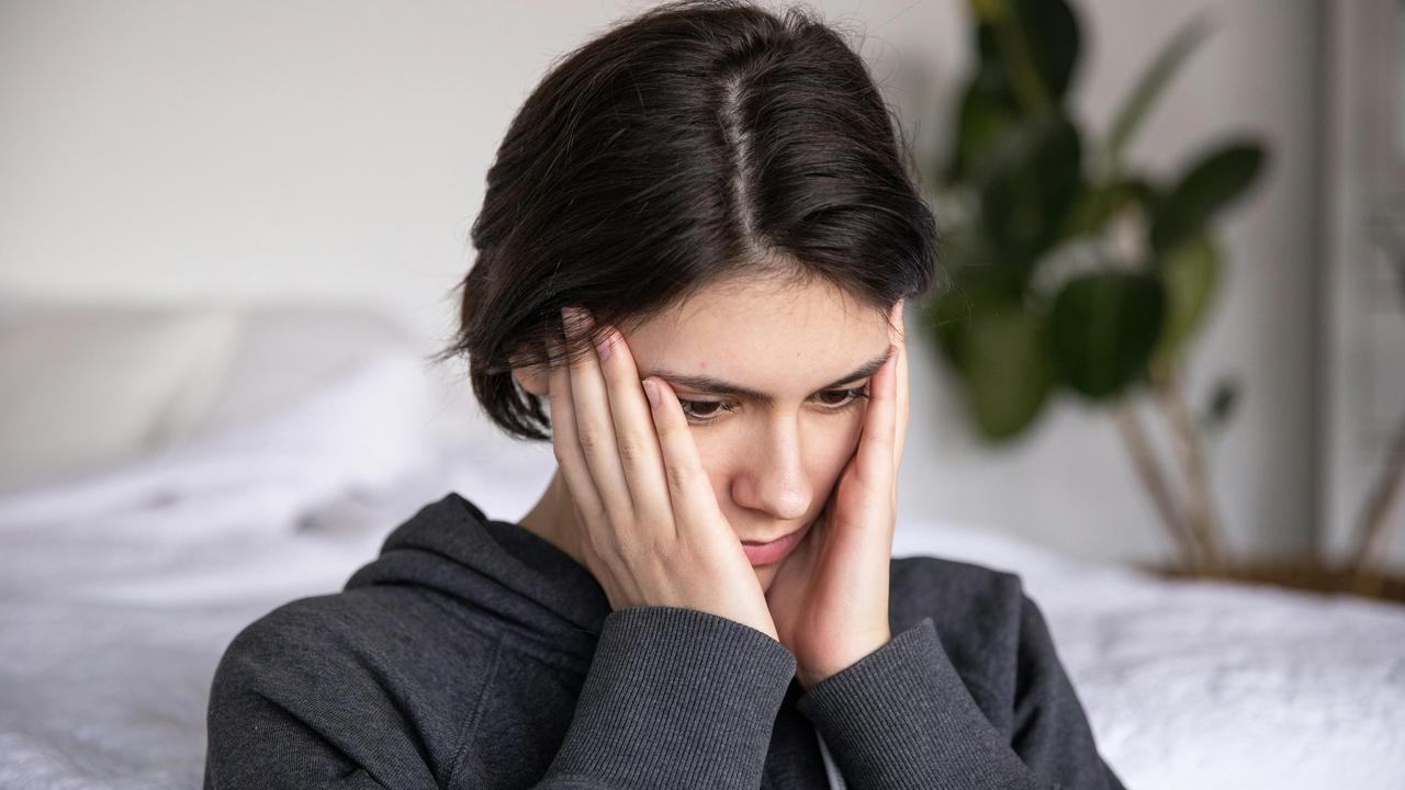 A woman holding her face with both hands, looking worried.