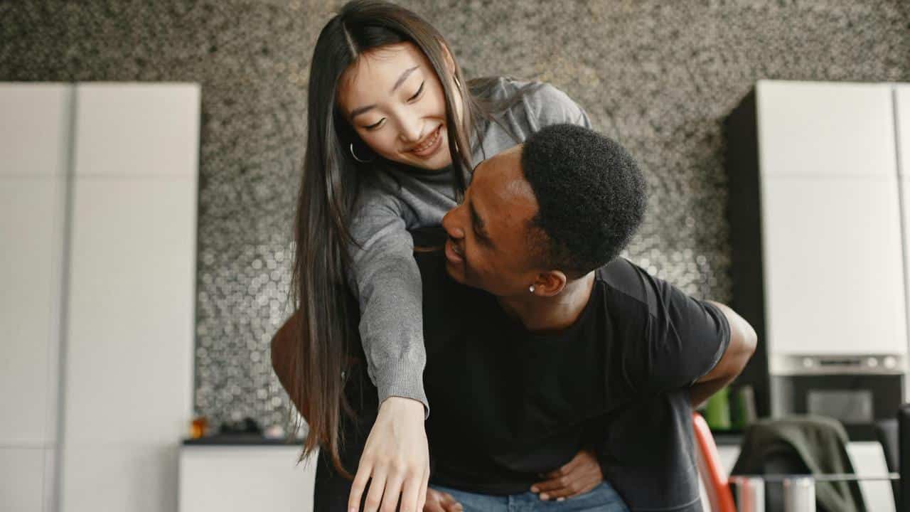 A couple playfully hugging in a kitchen.