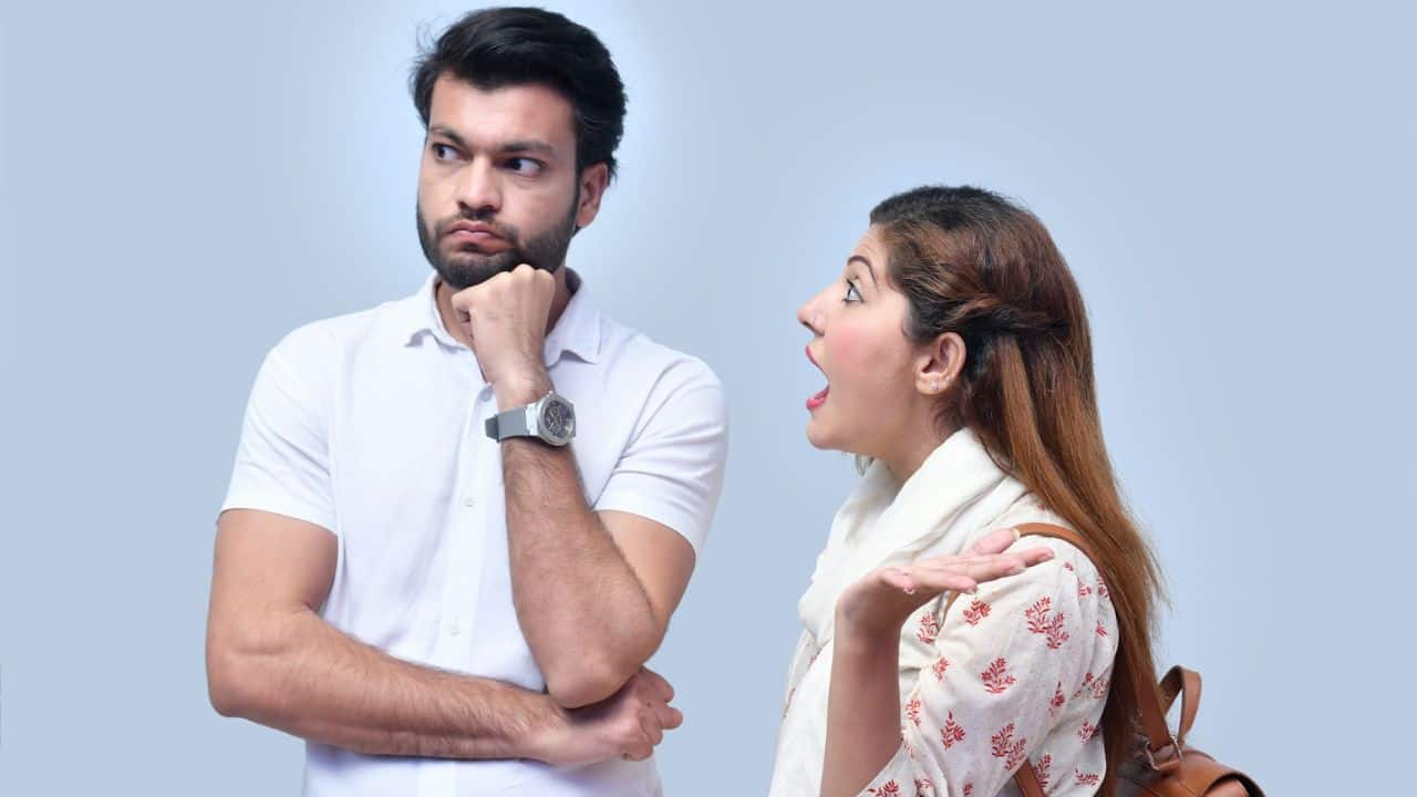 A man with a pensive expression looks away from an expressive, talking woman.