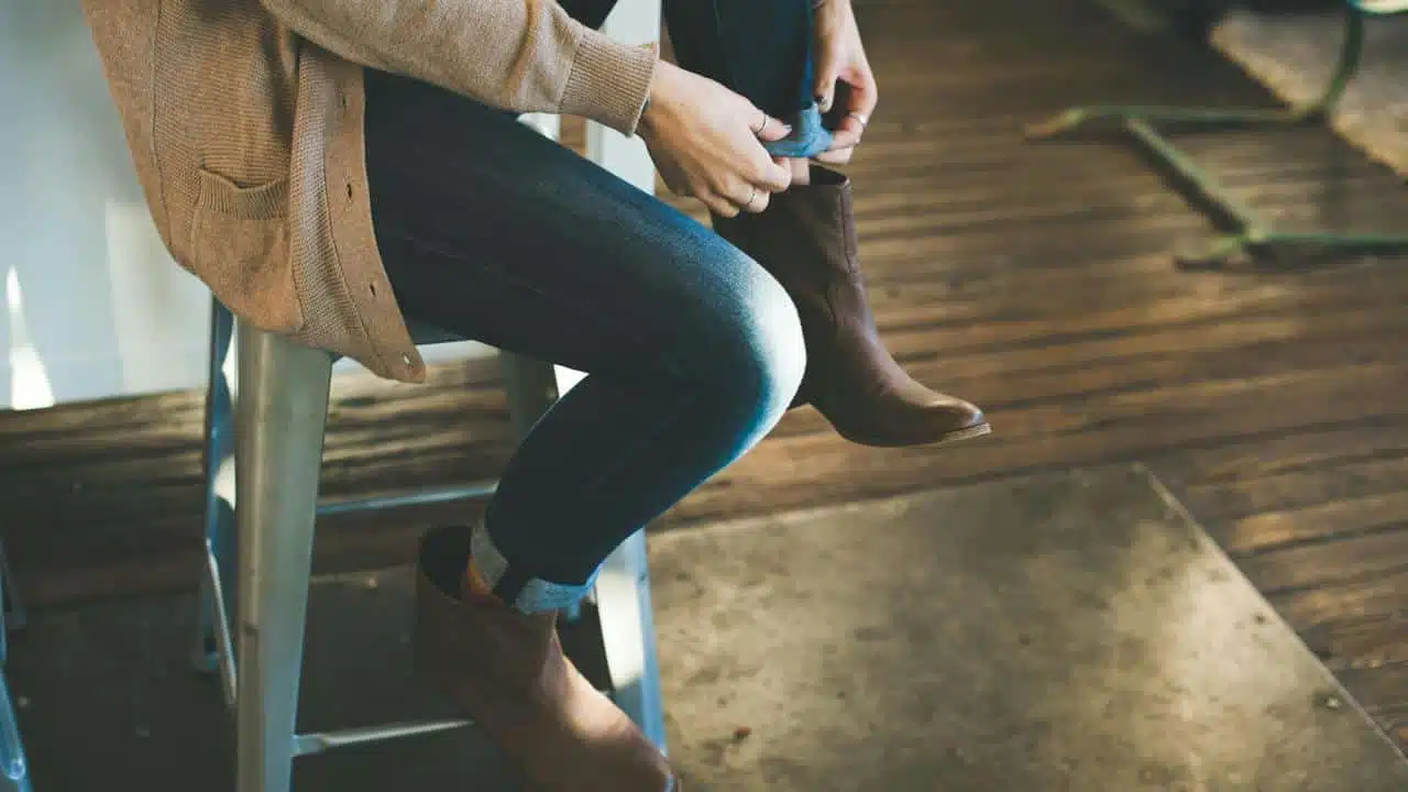 A person sitting and adjusting their boot.