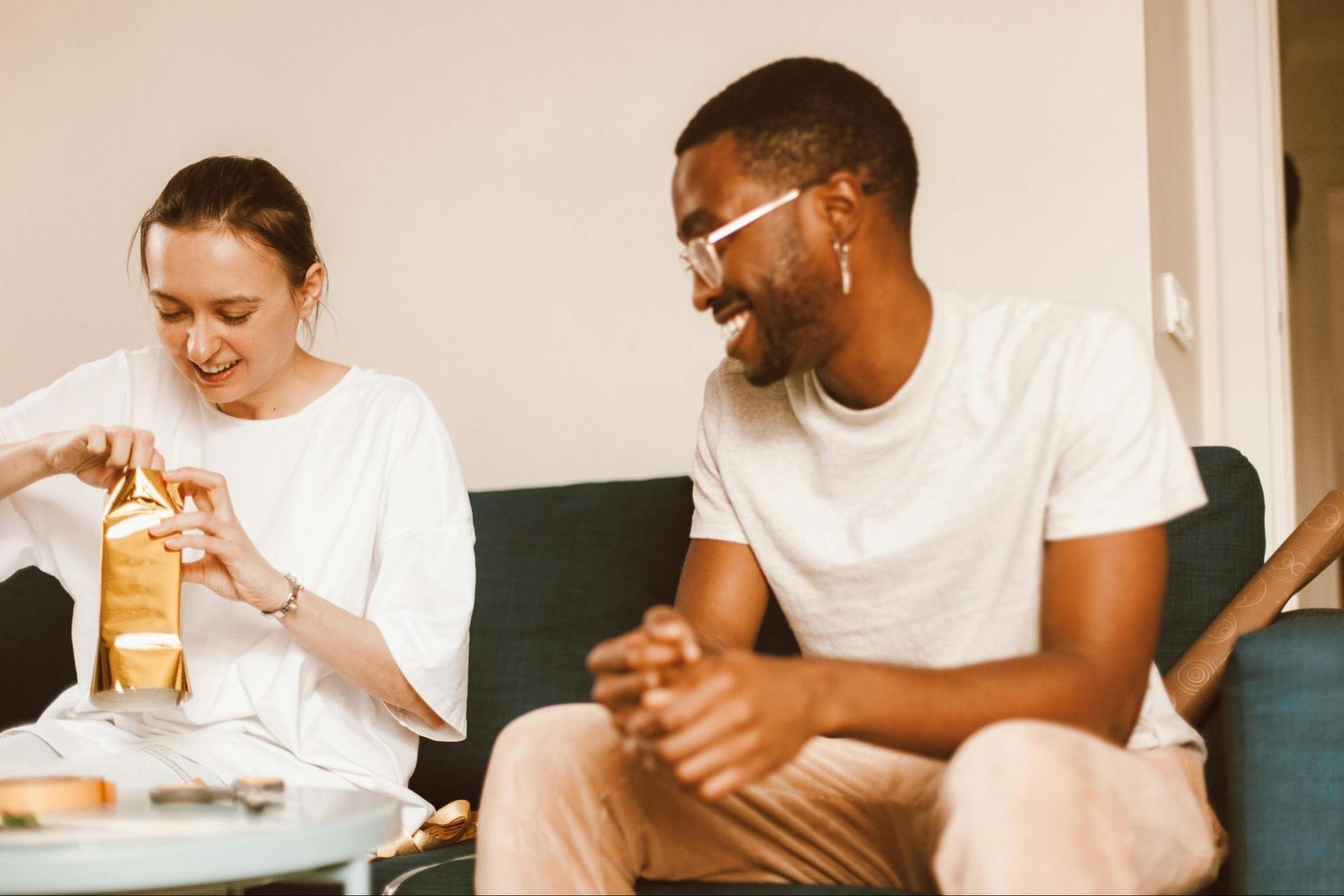 Woman opening a small, thoughtful gift from a man and smiling