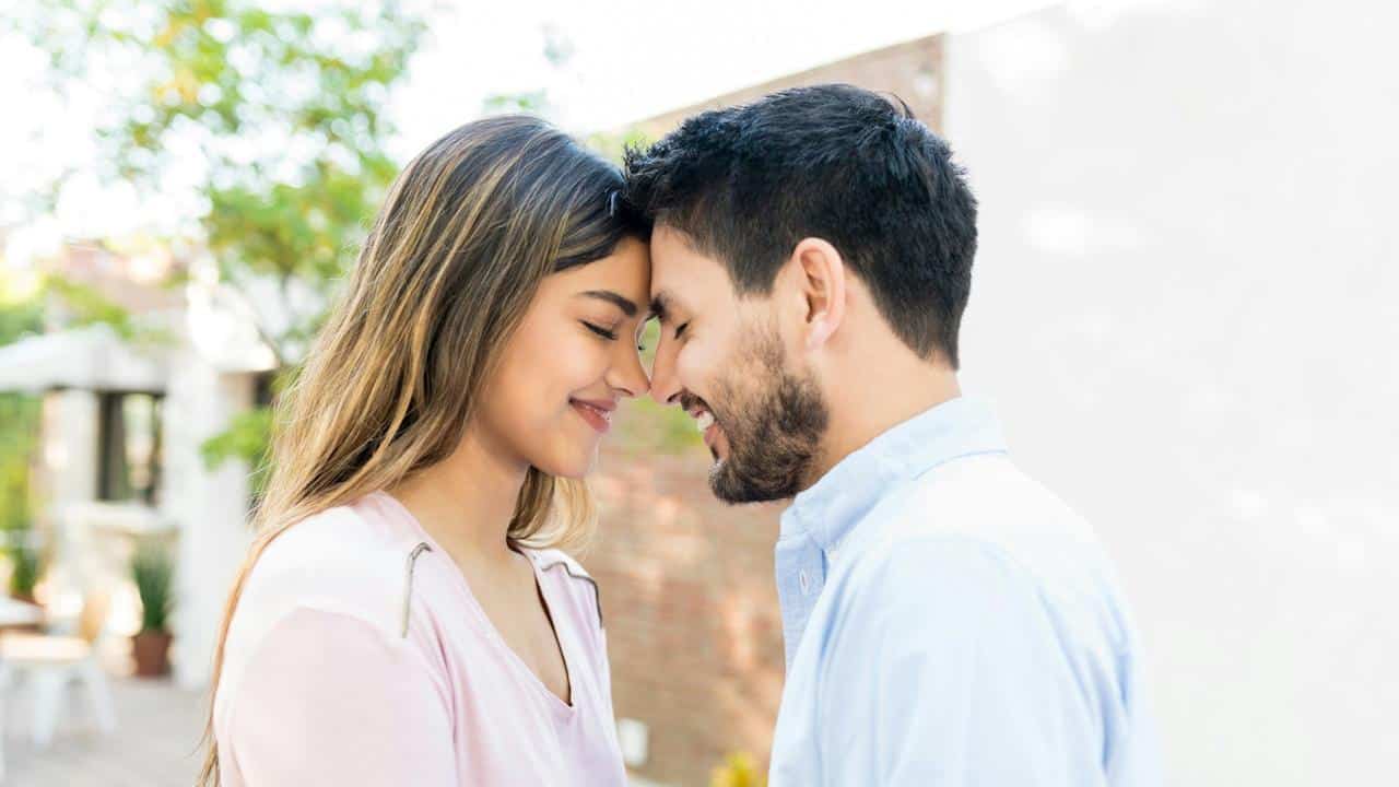 Side view of a romantic couple touching foreheads during a date.