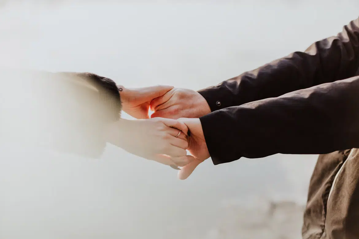 A woman reaching for a man’s hands.