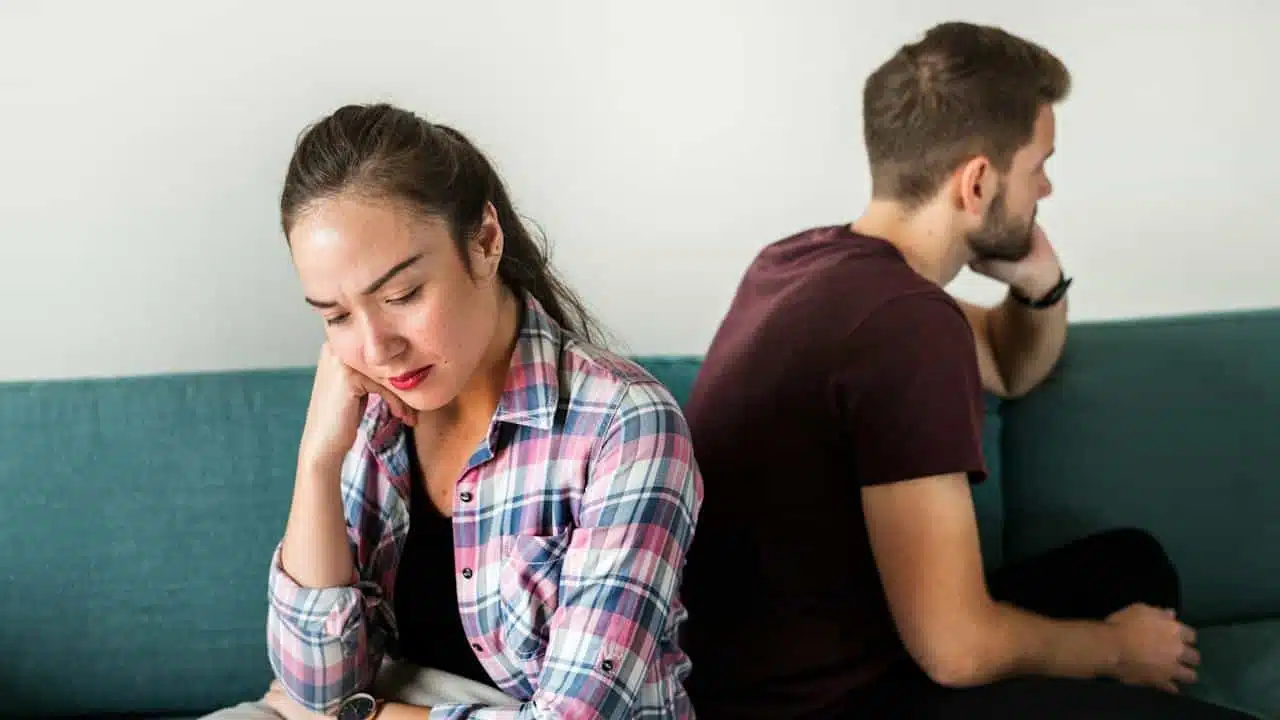 A couple sitting with their backs to each other and not talking.